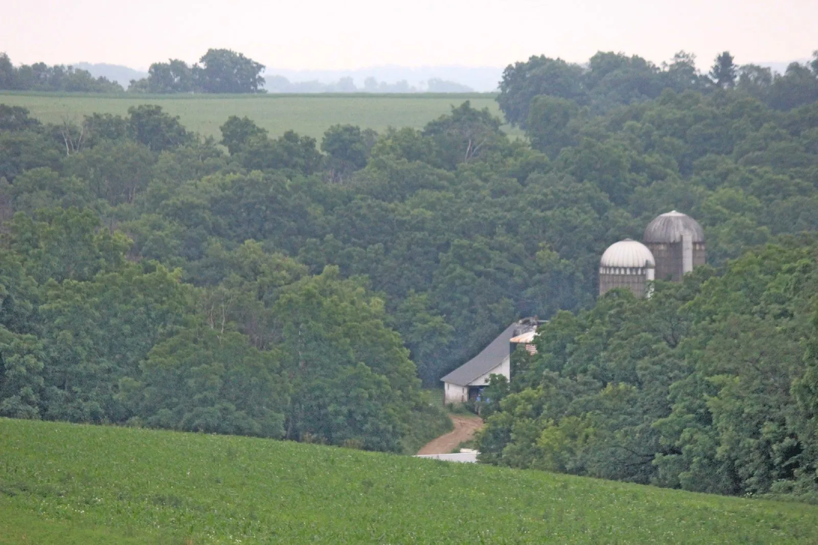 Green fields and wooded hills around farm silos from the Driftless HVAC photo archive
